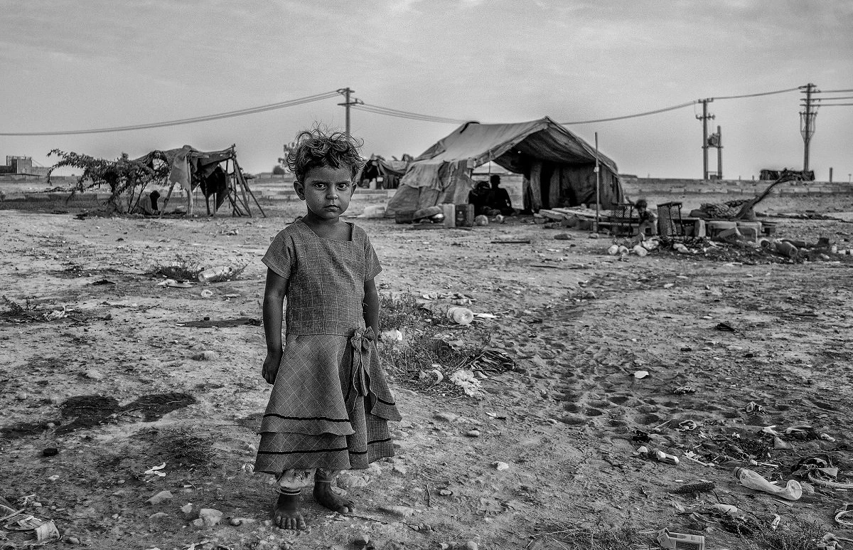 Child standing near tents from Poverty in Wealth