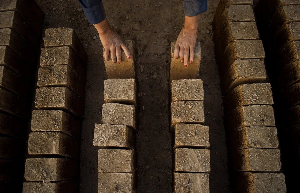 Hands stacking bricks in a brick workshop